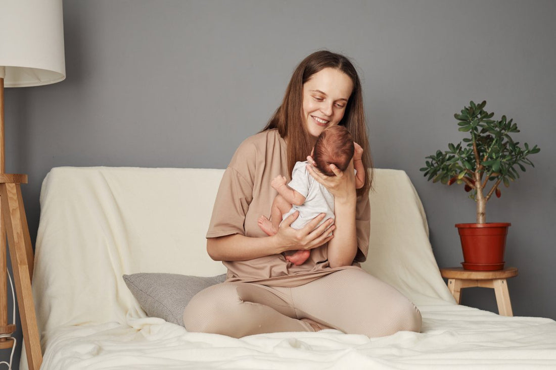 Smiling cheerful positive mother holding newborn baby