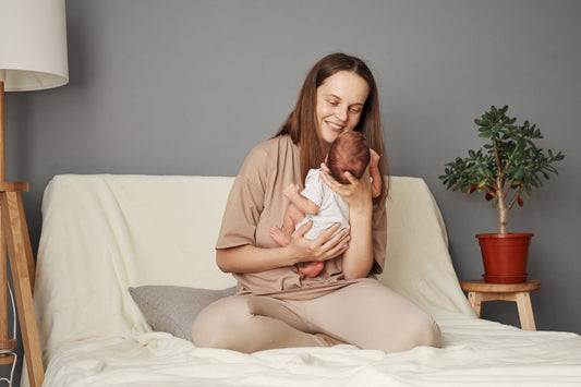Smiling cheerful positive mother holding newborn baby