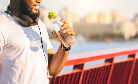 Stay Hydrated. Cheerful African American Sportsman Drinking Water On The Bridge, free space