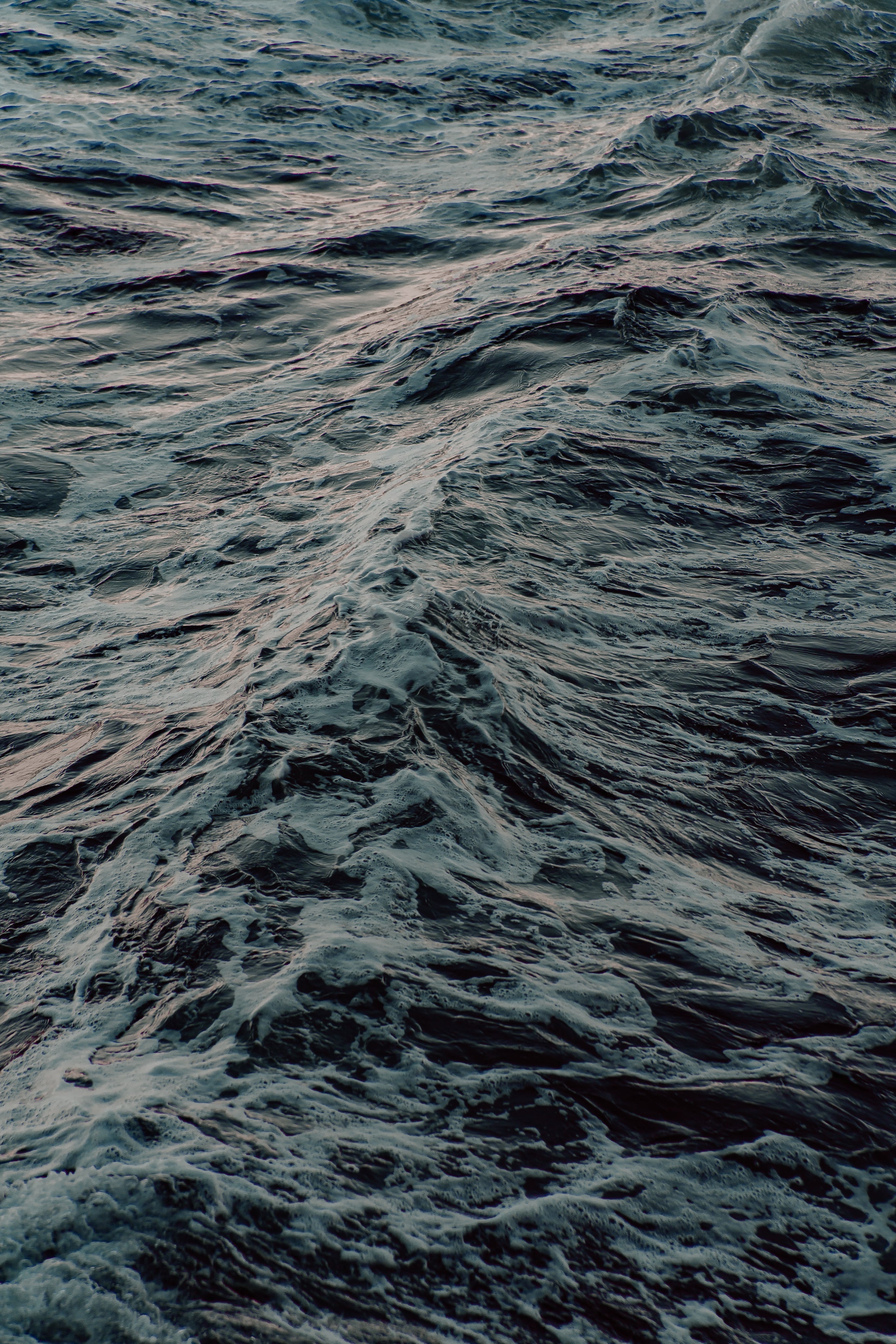 Close-up view of ocean waves with dark blue water and white foam, showing texture and motion of the sea surface.
