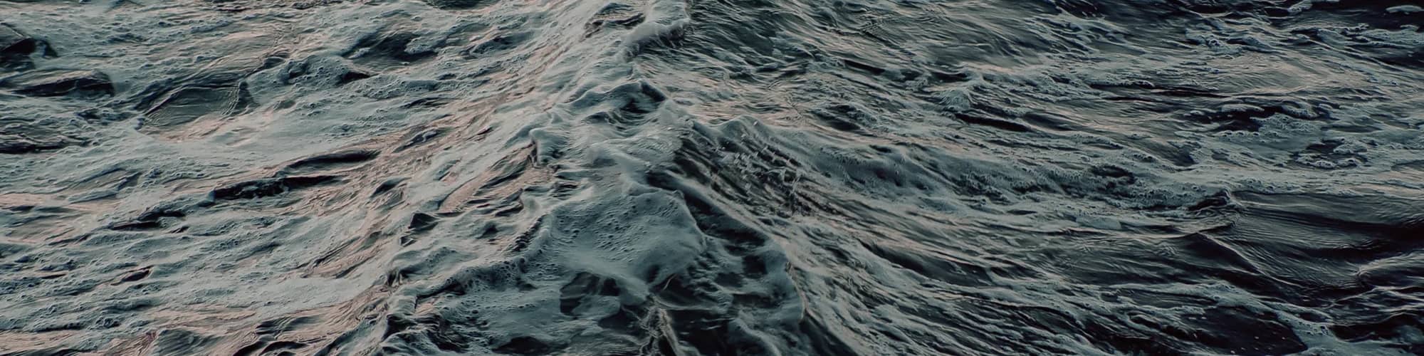 Close-up view of ocean waves with dark blue water and white foam, showing texture and motion of the sea surface.